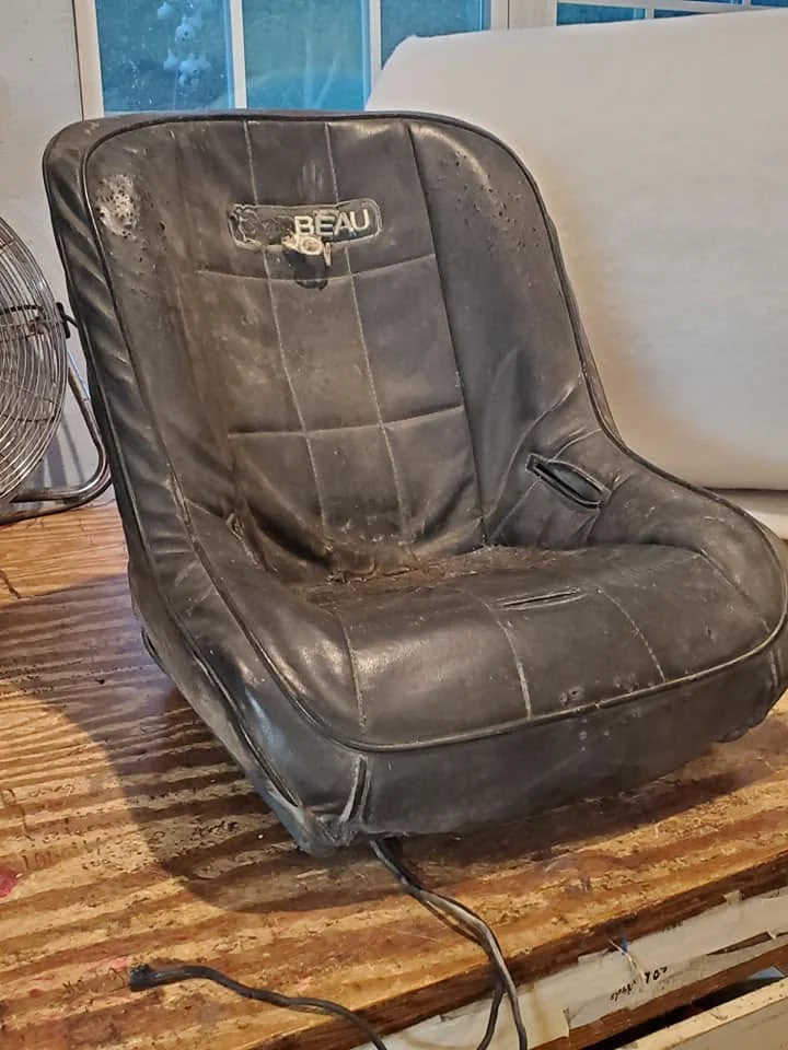 Worn black vehicle seat before reupholstery