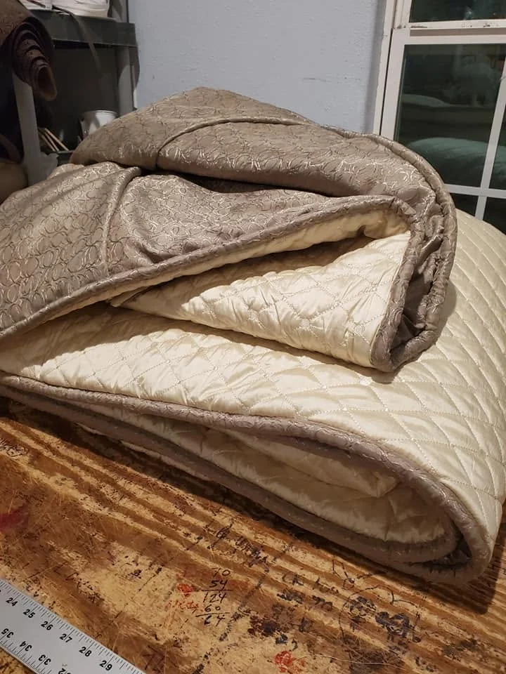 Layered upholstery fabric, padding, and cushion materials folded on a work surface