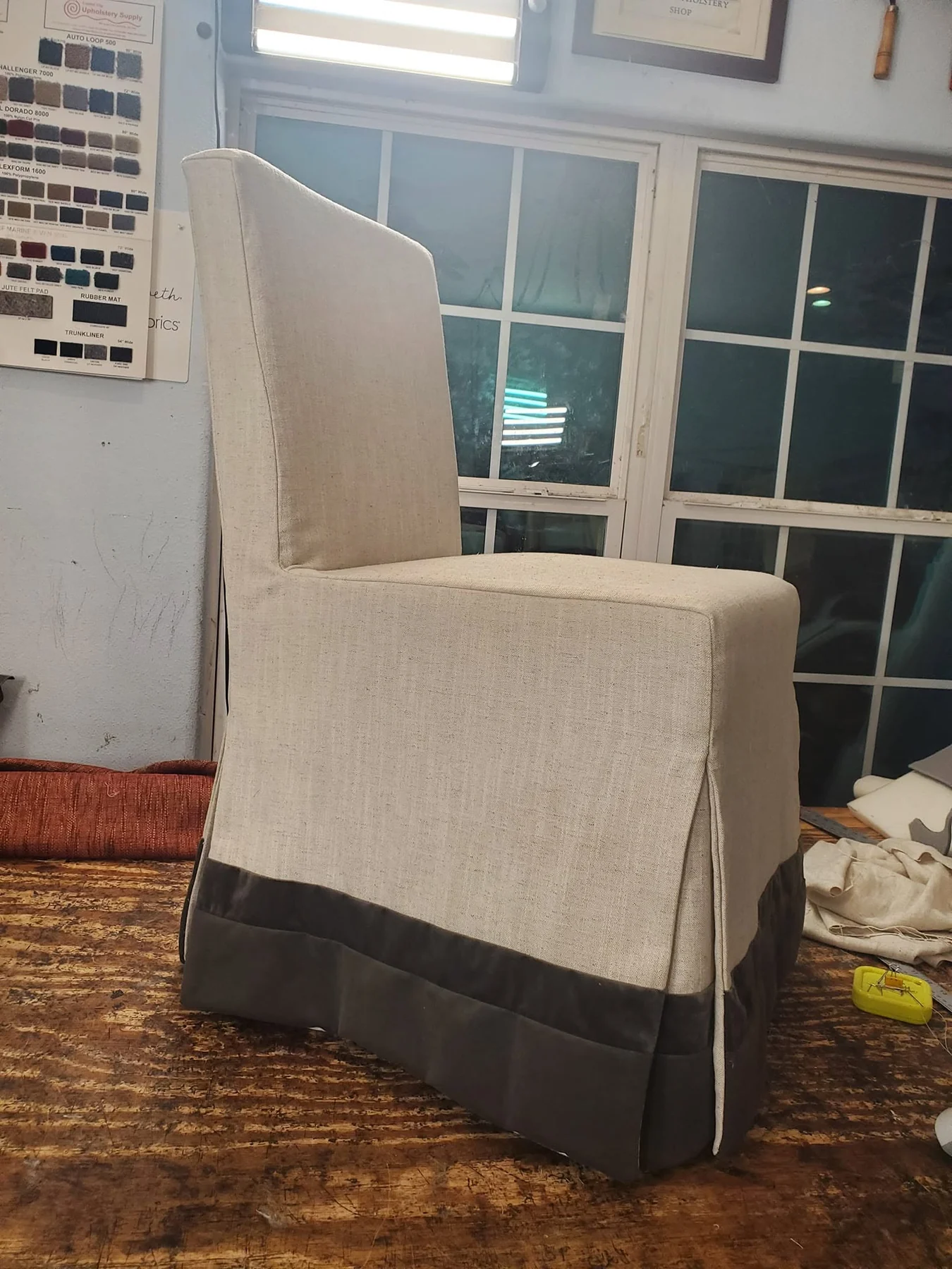 Dining chair fitted with a cream slipcover and contrasting dark hem